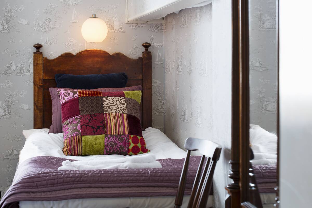 A neatly made bed with a wooden headboard, multiple pillows, and a white blanket.
