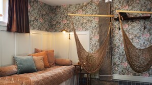 Een slaapkamer met een bed, een hangstoel en een wand met bloemenbehang.