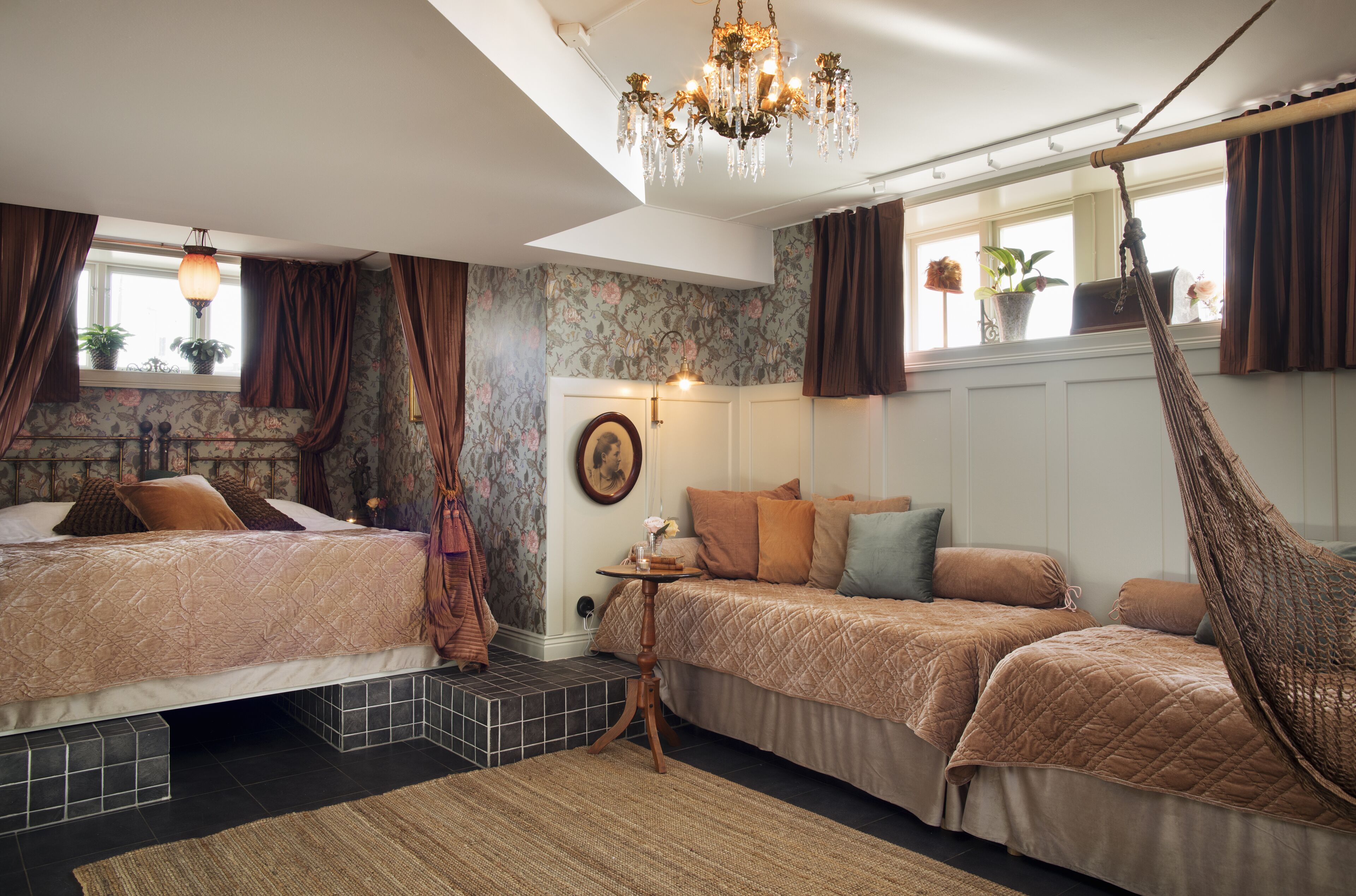 Ein Schlafzimmer mit zwei Betten, einem Hängesessel, einer Chandelier und einem Fenster mit Vorhängen.
