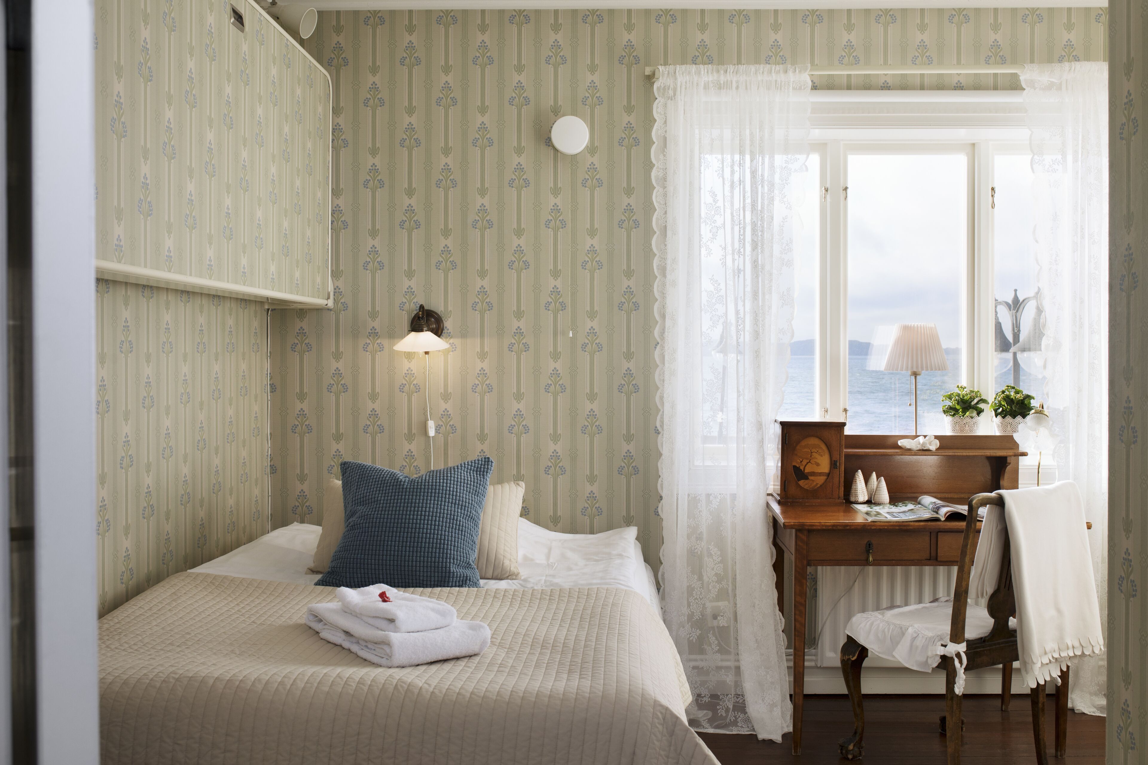 A neatly arranged hotel room with a bed, a desk, and a chair.