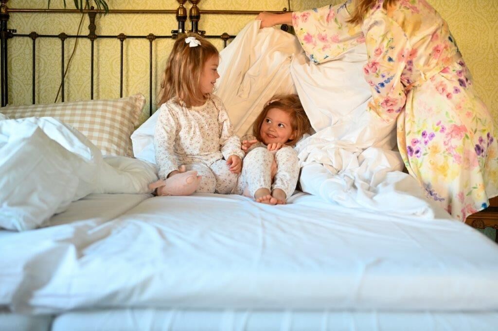 A bed with white linens and a metal headboard.