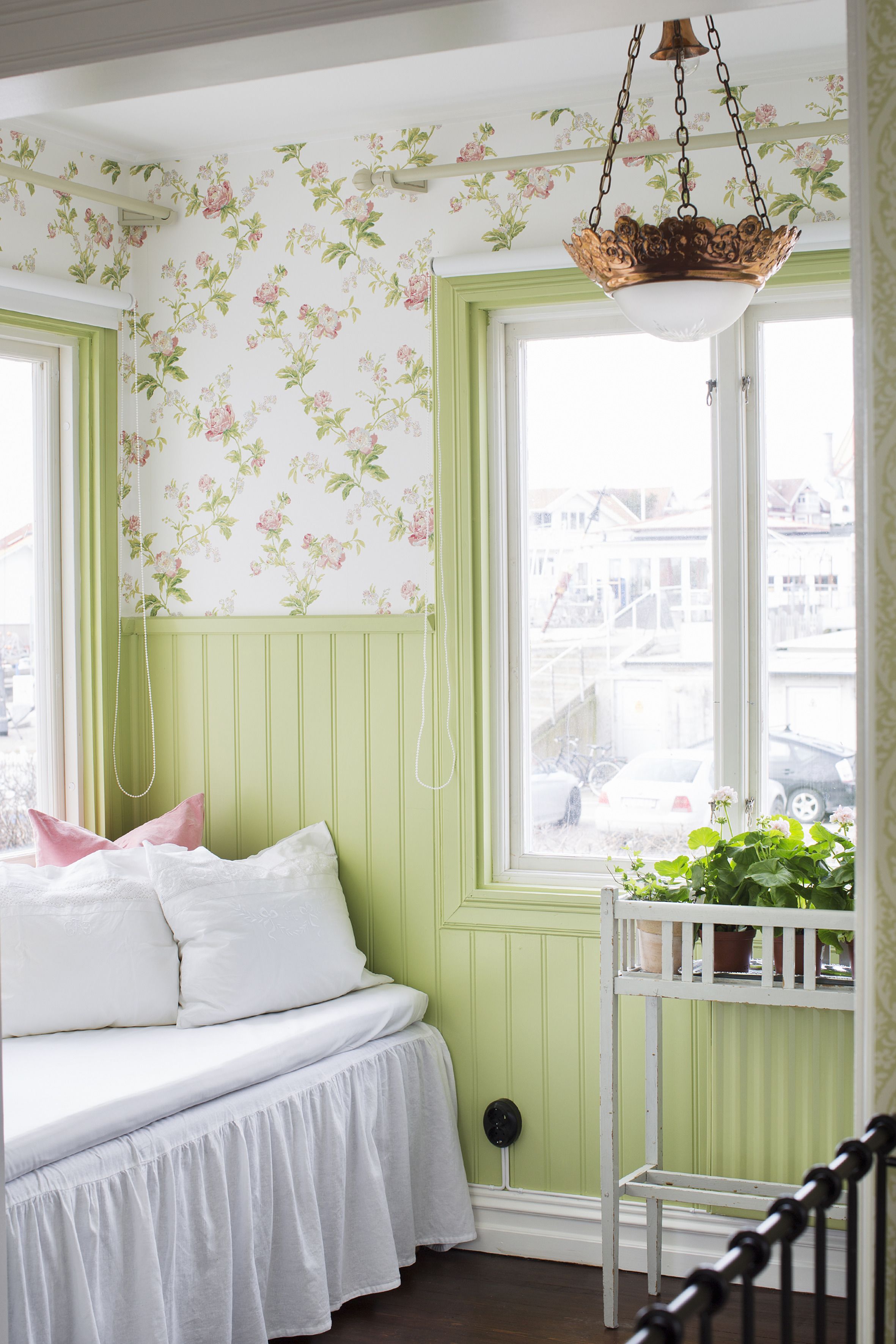 A room with a bed, a window with a view, and a hanging light fixture.