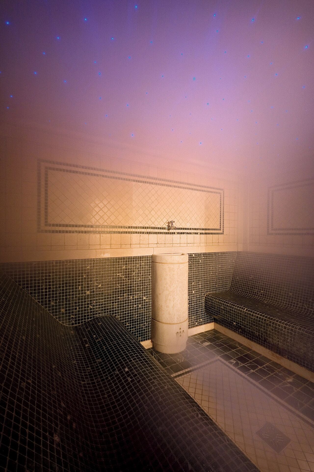 A room with a tiled floor, a central pillar, and a patterned wall.