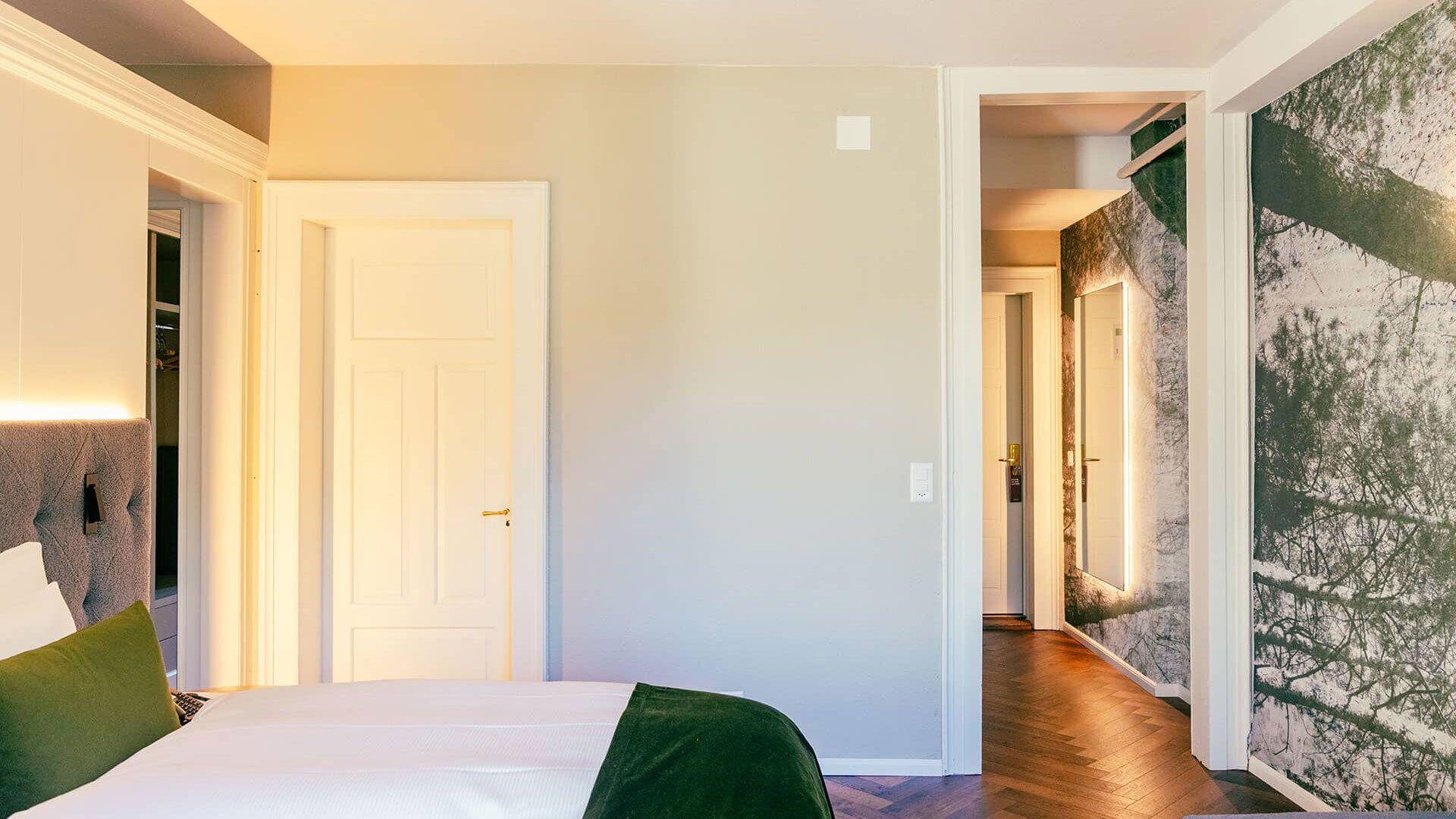 Una habitación de hotel con cama, una puerta y un pasillo que conduce a otra habitación.
