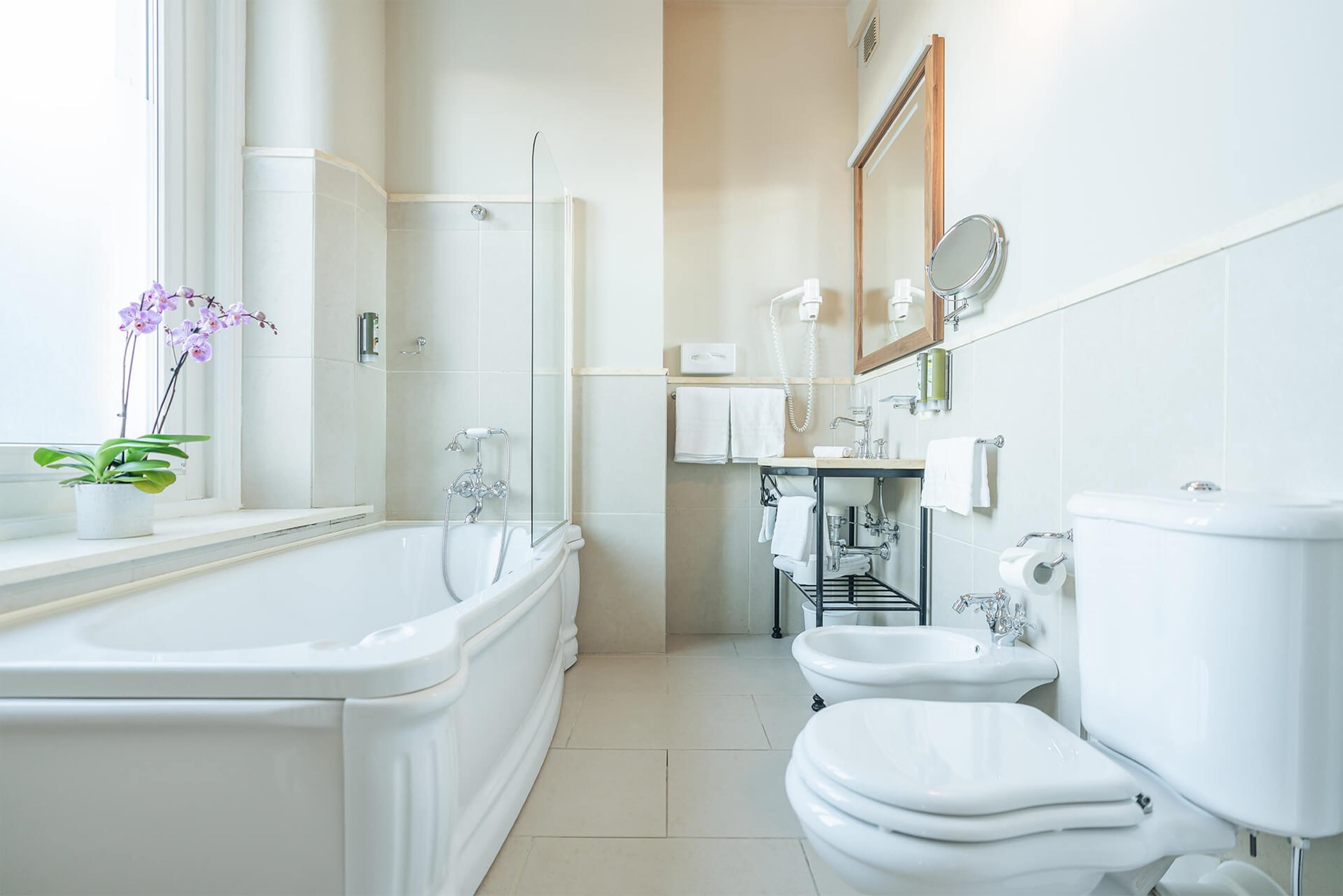 Ein modernes Badezimmer mit einer Badewanne, zwei Waschbecken, einer Toilette und einer Dusche.
