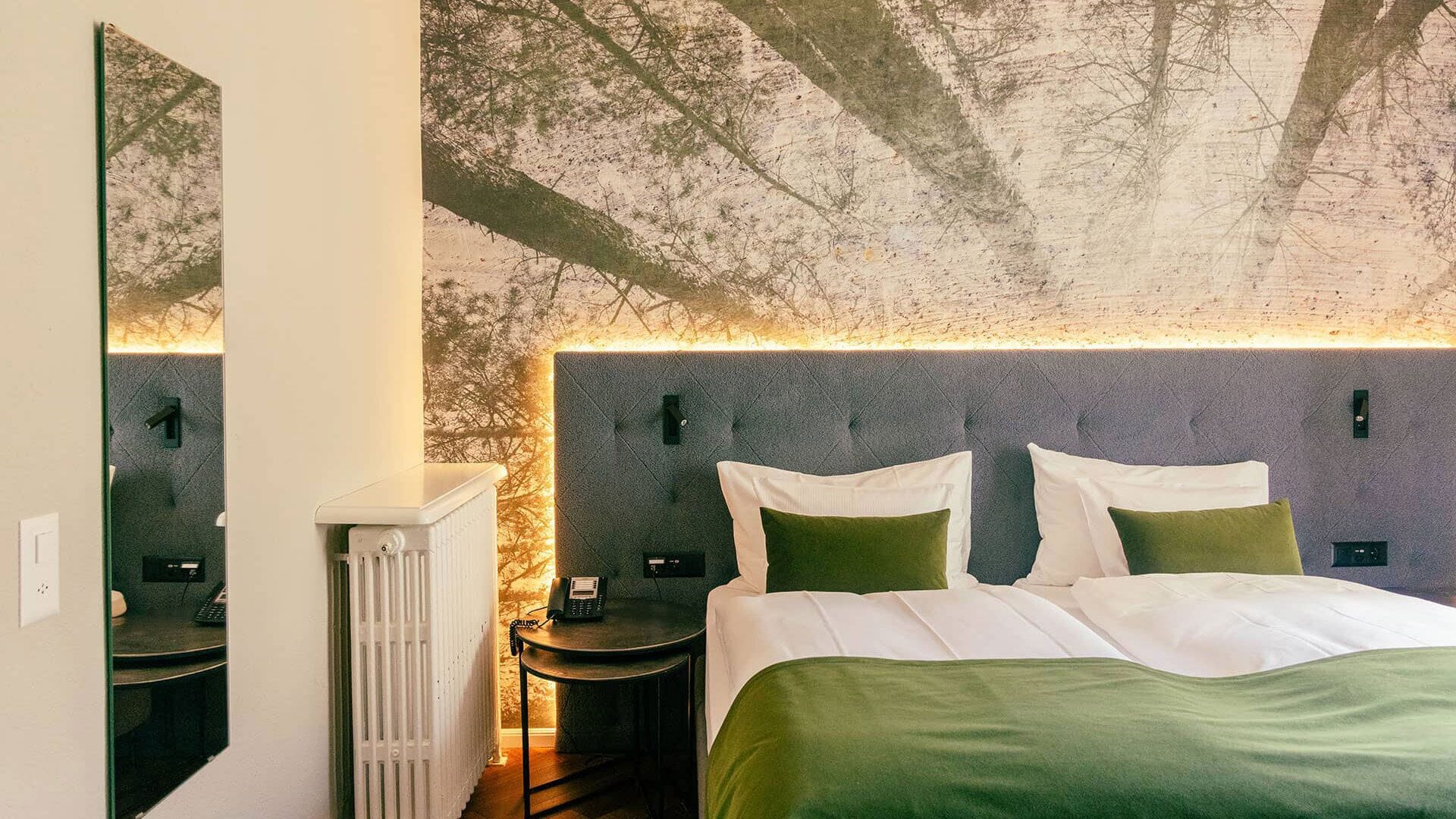 Una habitación de hotel con una cama grande, una mesita de noche, un espejo y un radiador.