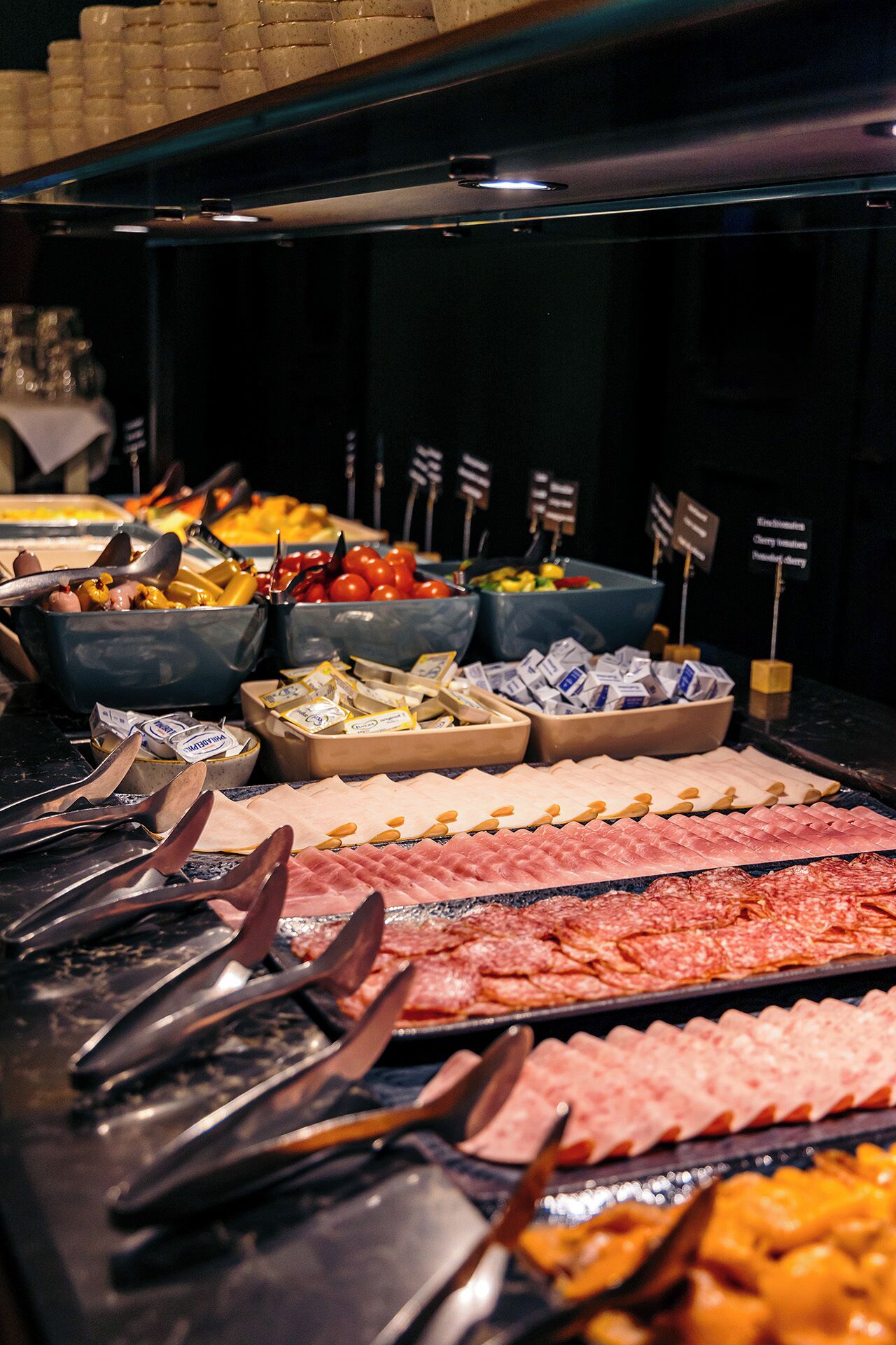 Un buffet proposant une variété de plats, notamment des viandes, des fromages et des fruits.