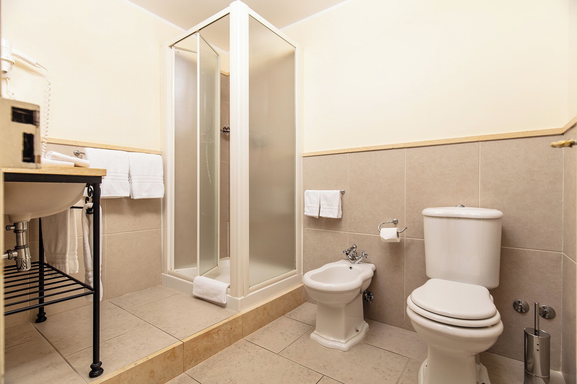A modern bathroom with a shower, bidet, toilet, and a sink with a towel rack.