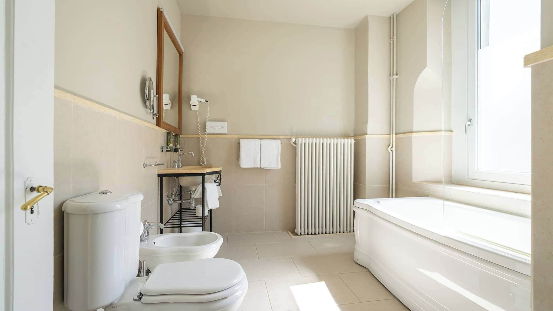 A modern bathroom with a toilet, bidet, sink, and bathtub.