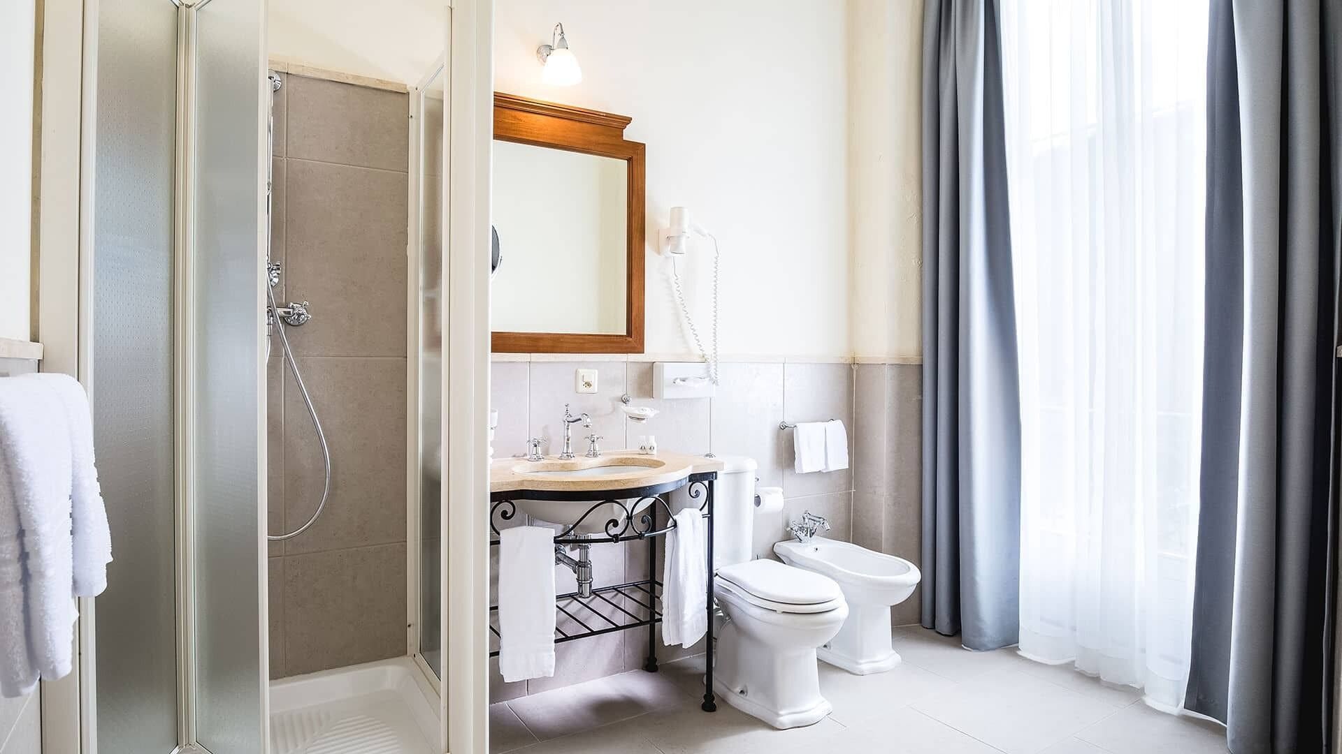 Een moderne badkamer met een douchecabine van glas, een wastafel met opbergruimte, een toilet en een spiegel boven de wastafel.