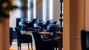 A dining area with a chandelier, multiple tables, and chairs. - Hotel Reine Victoria (St. Moritz)