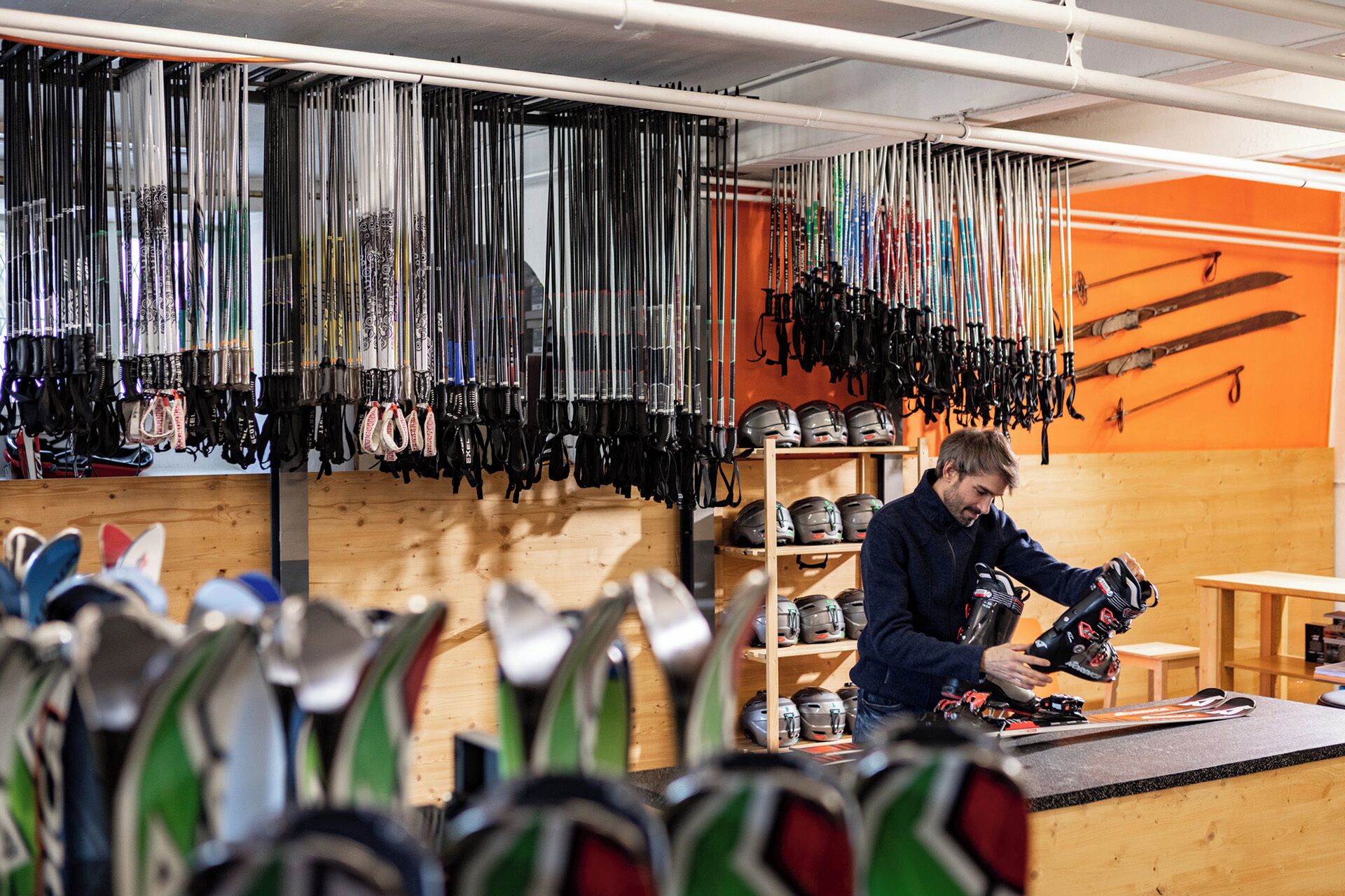 Un magasin d’articles de ski où l’on peut trouver différents types de bâtons de ski et de casques, exposés sur des étagères et suspendus au plafond.