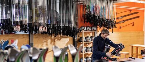 Un magasin d’articles de ski où l’on peut trouver différents types de bâtons de ski et de casques, exposés sur des étagères et suspendus au plafond.