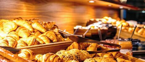 A buffet with various baked goods like croissants and bread.