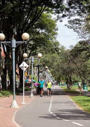 A paved pathway lined with trees and street lamps, with people jogging. - Jazz Apartments Luxury Suites (Bogotá)