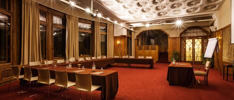 Un salón de conferencias con una larga mesa, sillas y una pizarra.
