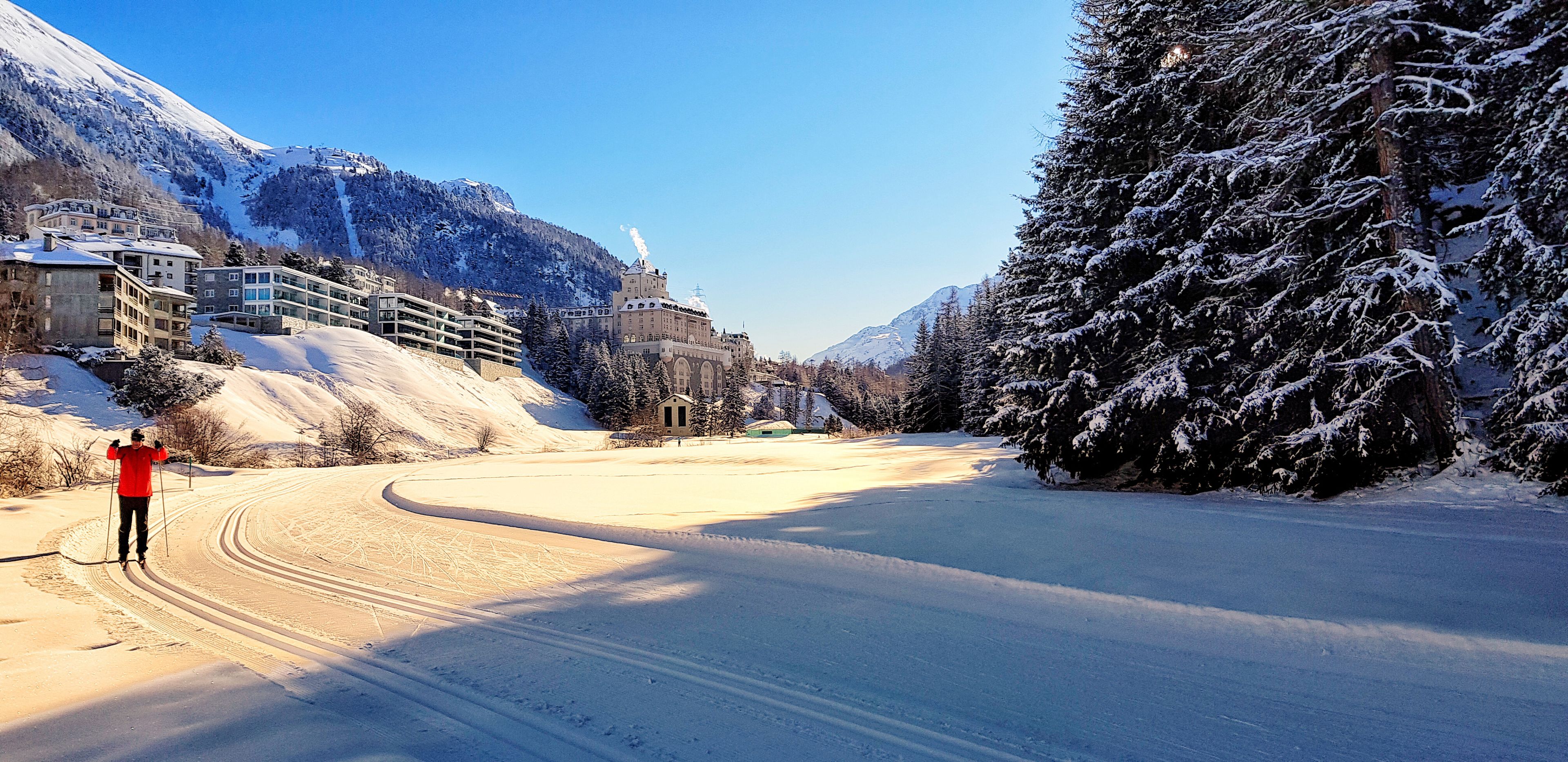 A snow-covered landscape with a ski resort, including buildings and trees.