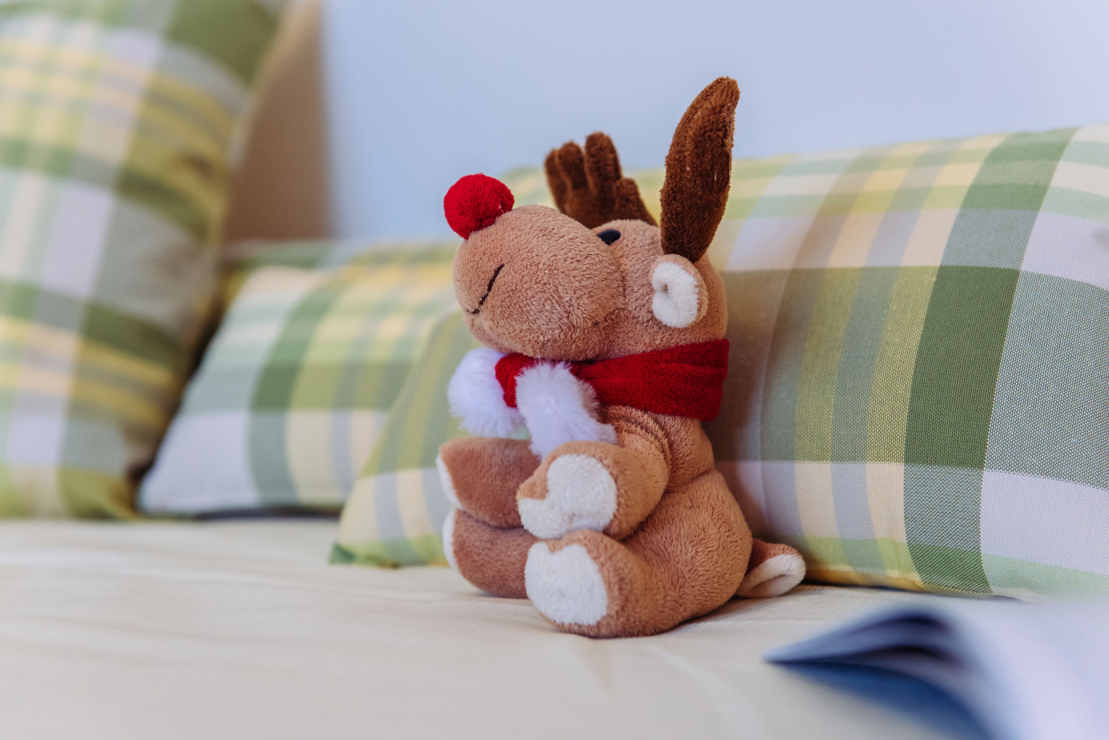 A plush toy on a bed with checkered pillows.
