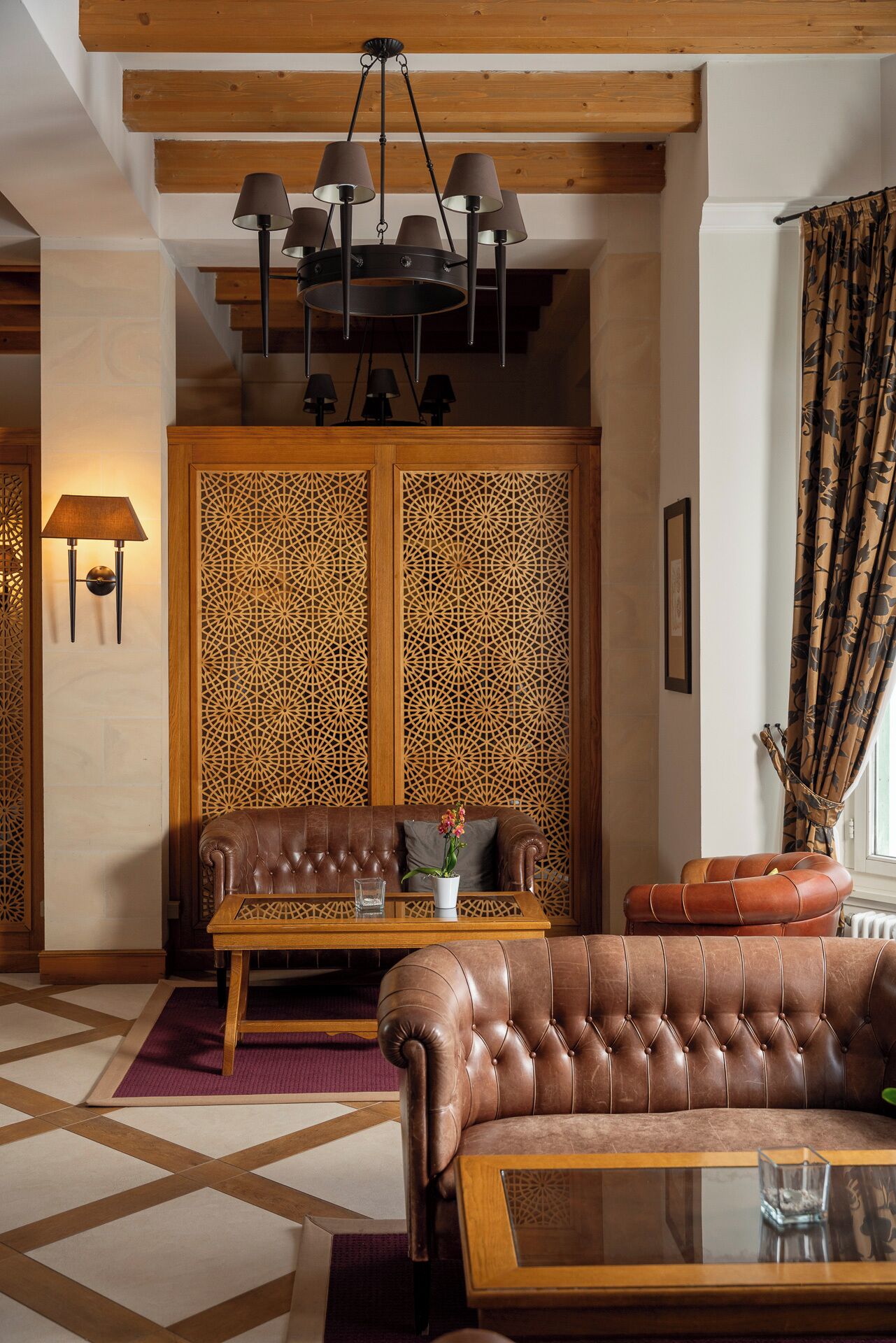 A cozy living room with a brown leather sofa, a wooden coffee table, and a patterned wall divider.