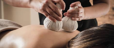 A massage therapy session with a person lying face down receiving a back massage.