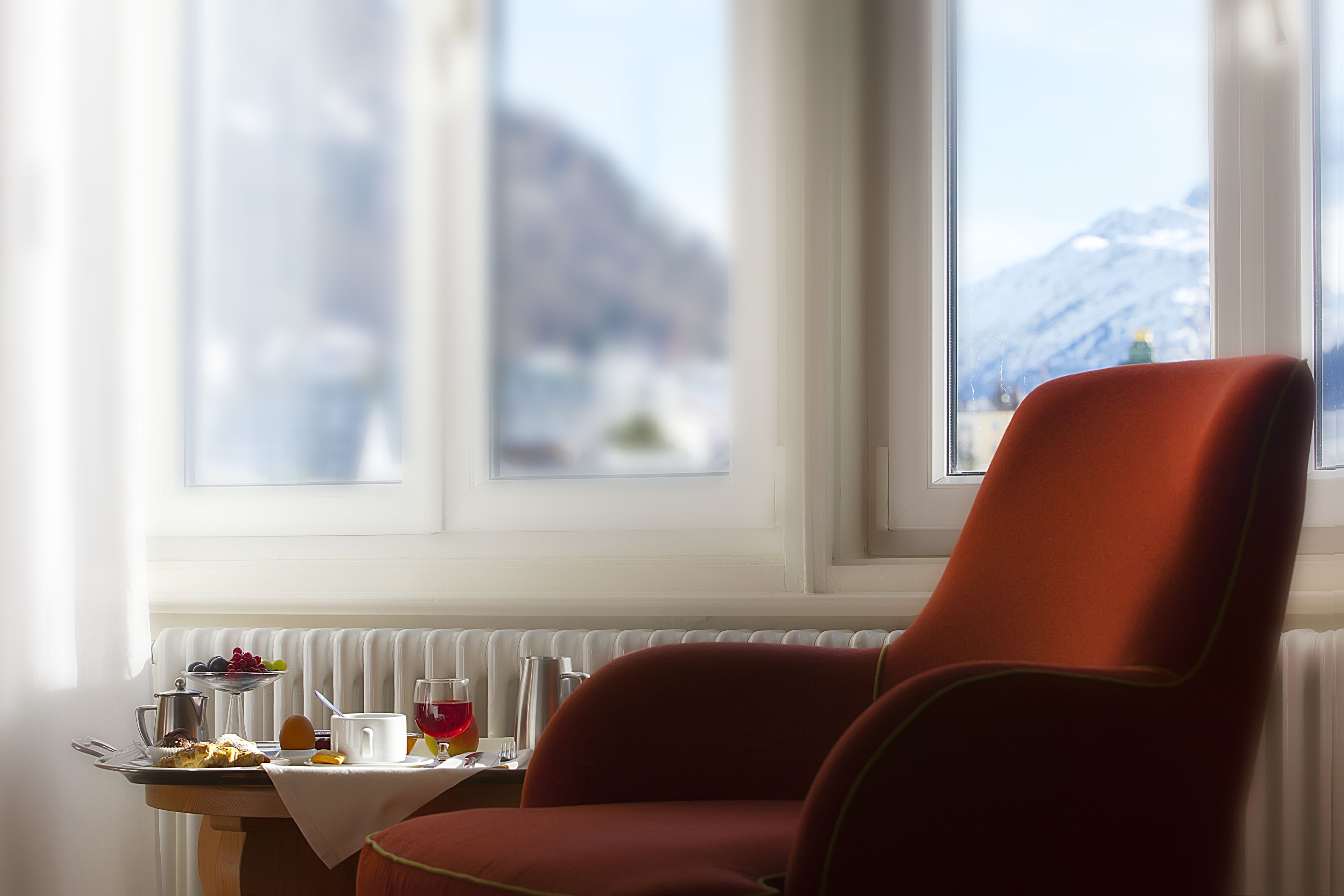A dining area with a table set for breakfast, a chair, and a view of a mountain.