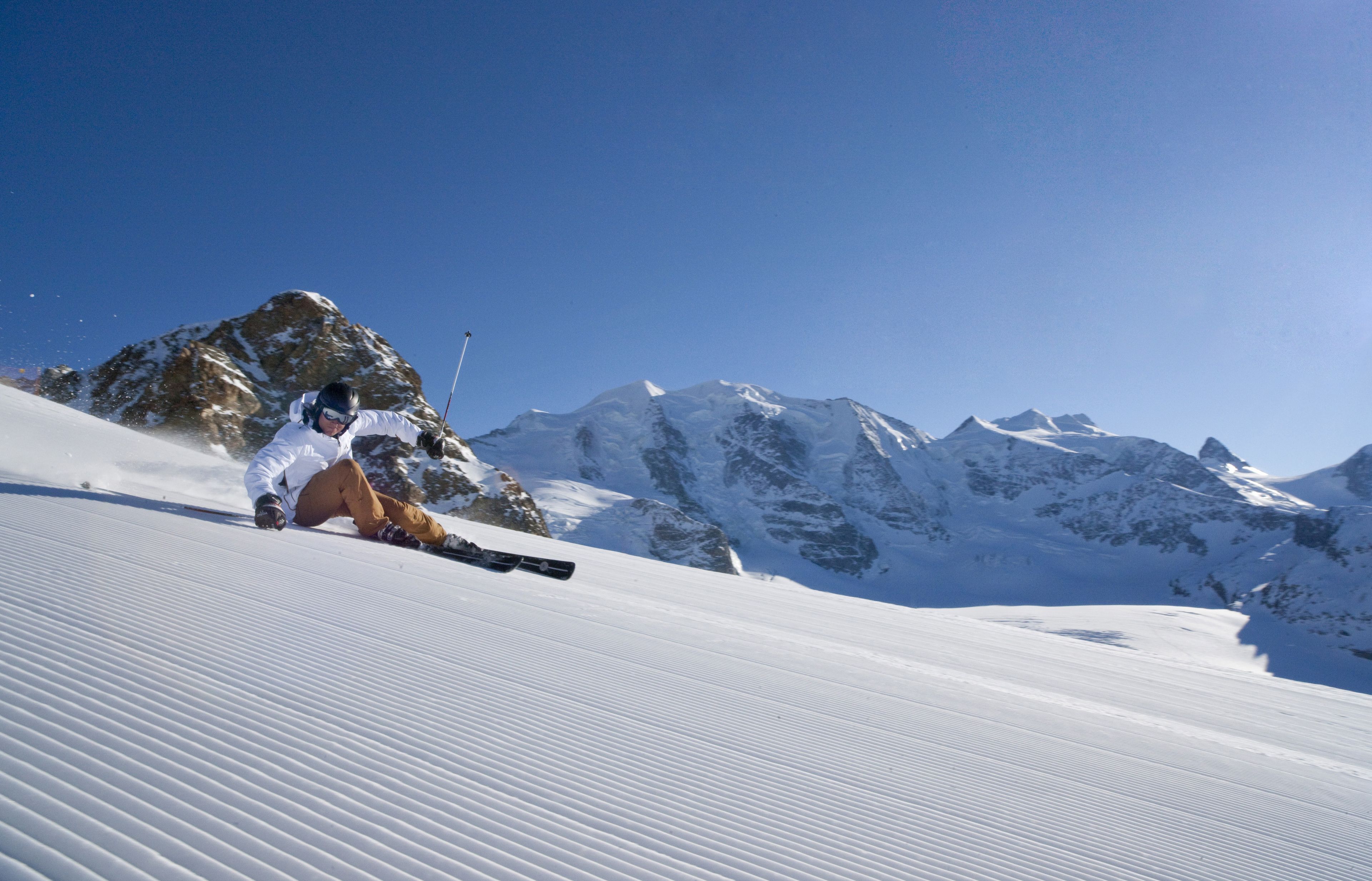 A person skiing on a snow-covered slope with mountains in the background.