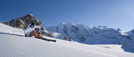 A person skiing on a snow-covered slope with mountains in the background.