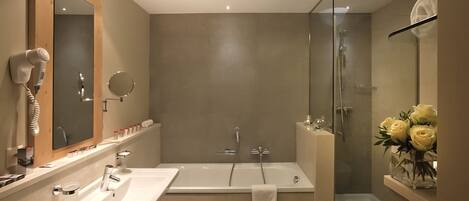 A modern bathroom with a large mirror, two sinks, a shower, and a glass-enclosed shower stall.