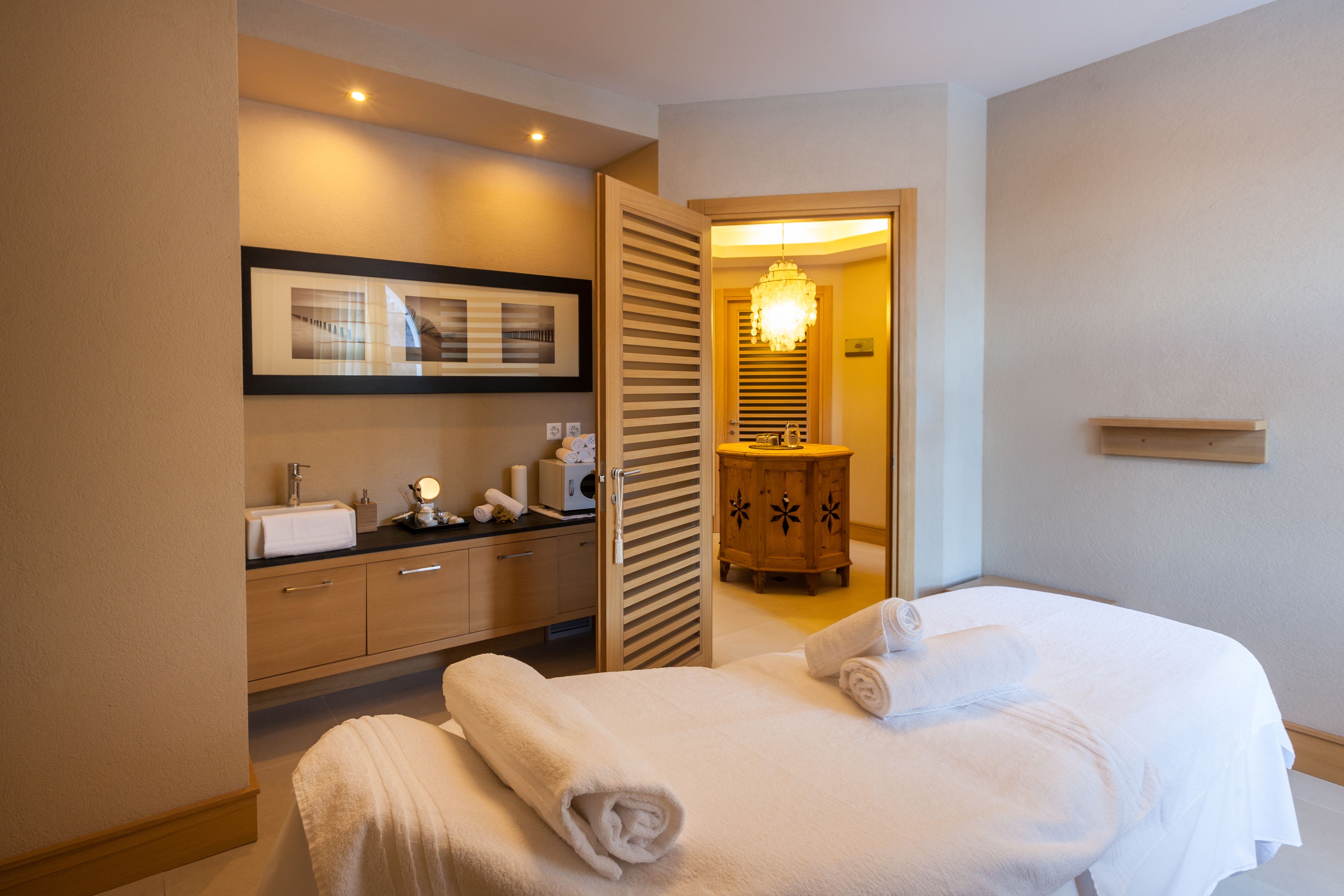 Ein Hotelzimmer mit Bett, Bad und einem Gang zu einem weiteren Zimmer.