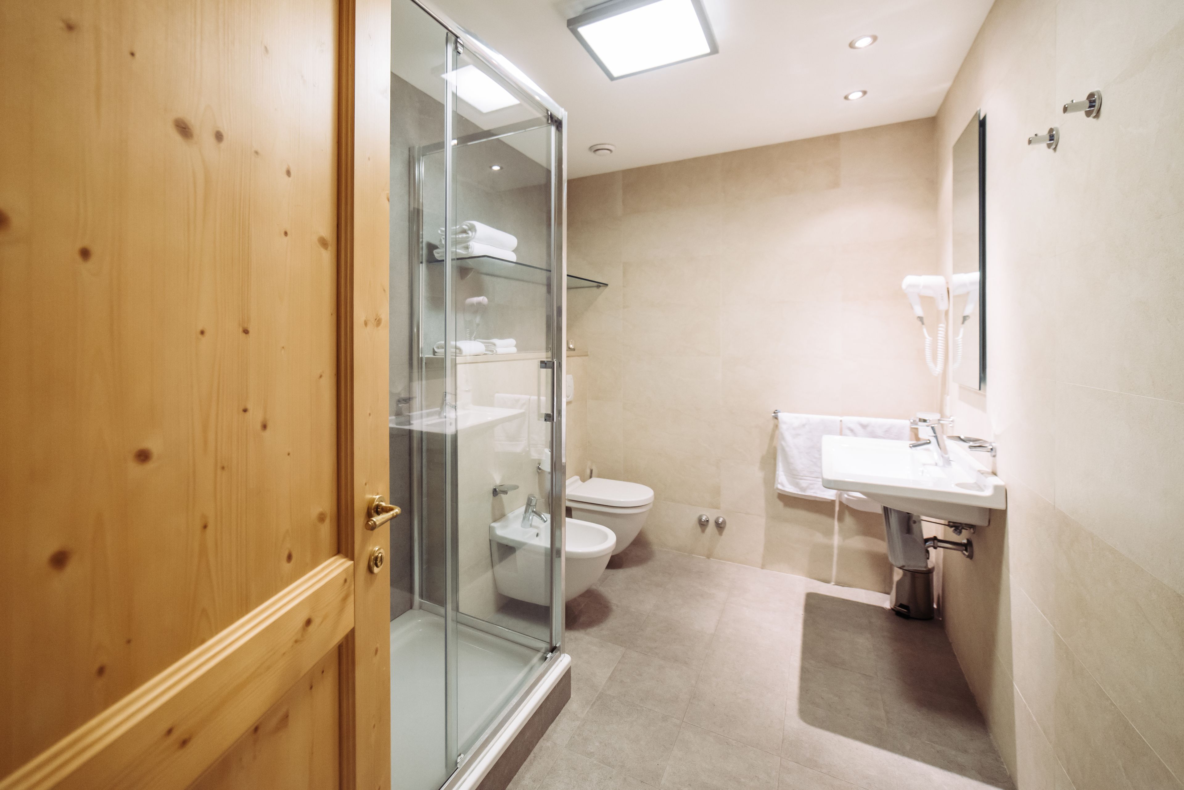 A modern bathroom with a glass shower enclosure, a toilet, and a sink with a mirror.