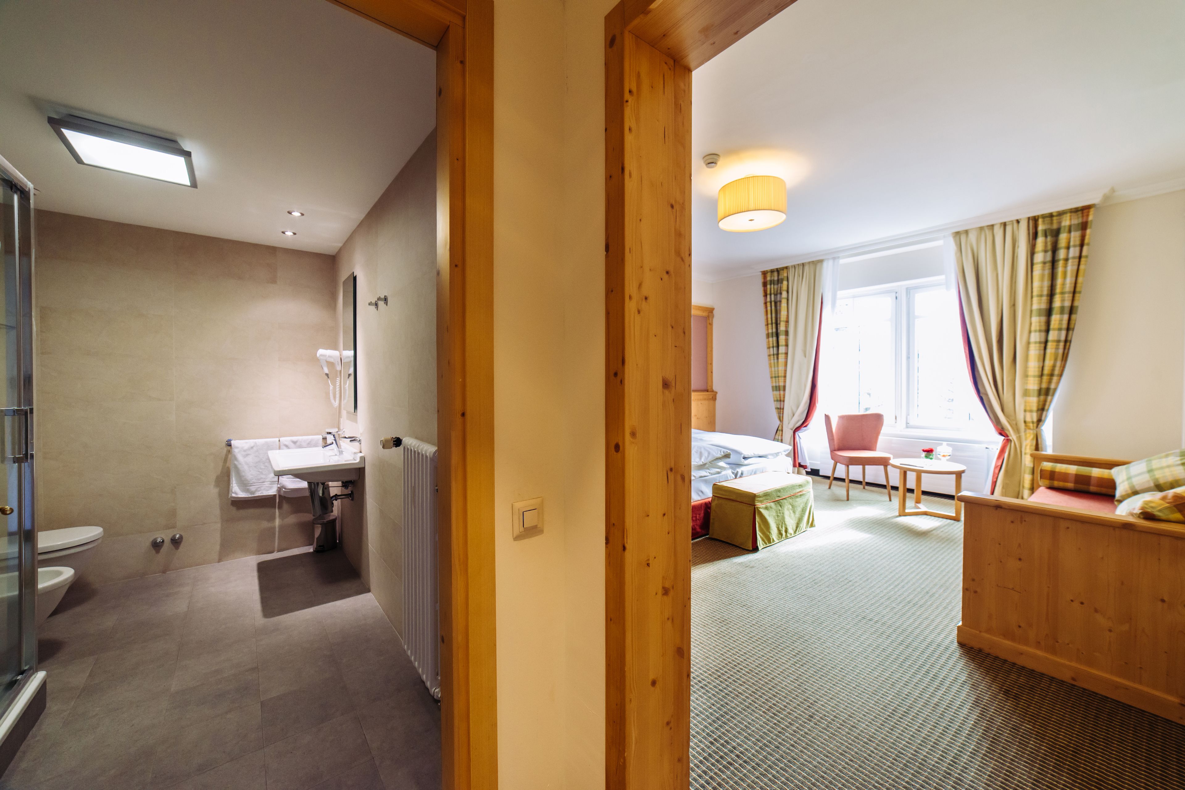 A hotel room with a bathroom, a bed, a small table, and a chair.