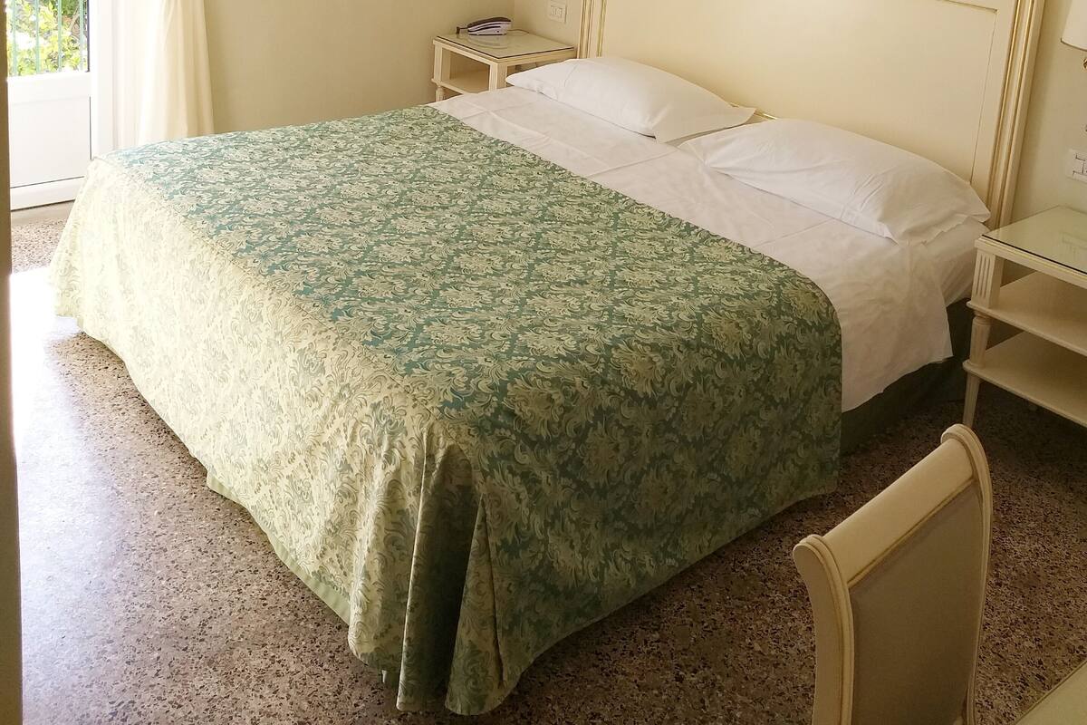 A hotel room with a bed, a nightstand, a lamp, and framed pictures on the wall.