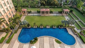 An aerial view of a hotel with a large swimming pool, sun loungers, and a well-maintained lawn area. - Radisson Blu Hotel Rudrapur (Kichha)