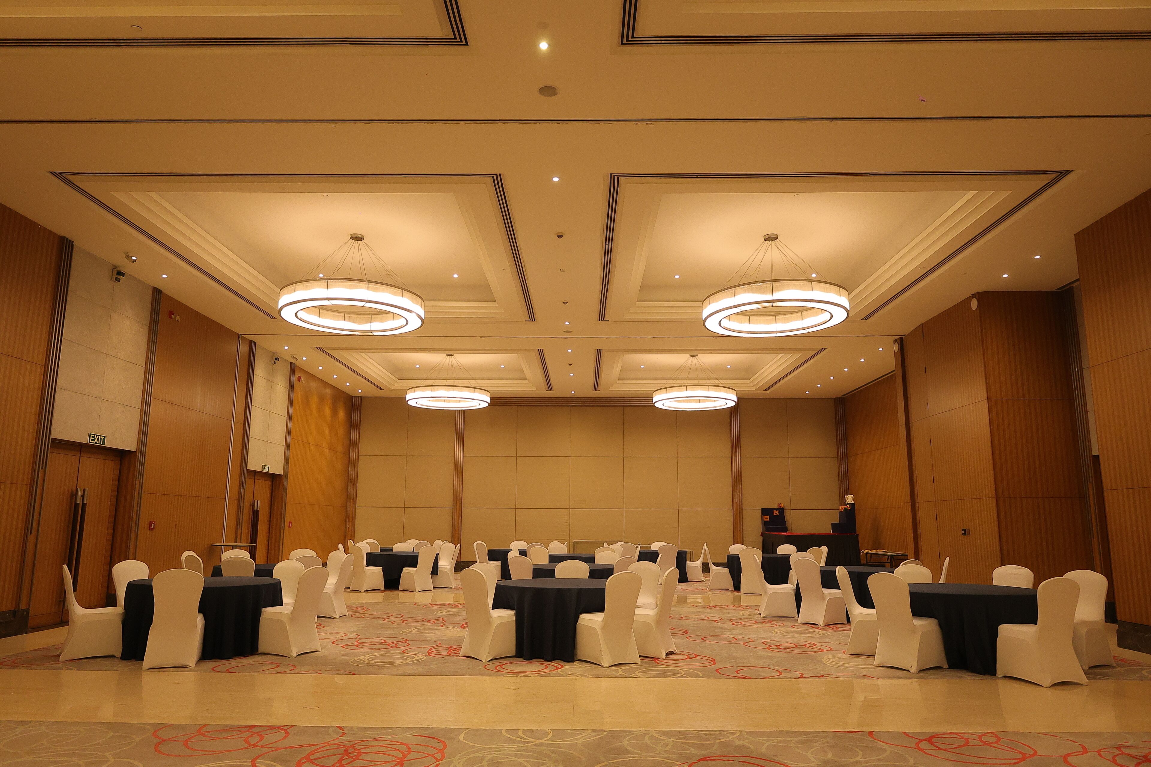 A conference room with round tables, white chairs, and a carpeted floor.
