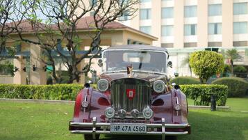 A vintage car parked on a grassy area with a building in the background.
