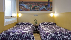 Ett hotellrum med två sängar, en målning med en stadsbild ovanför sängarna och ett fönster med persienner.