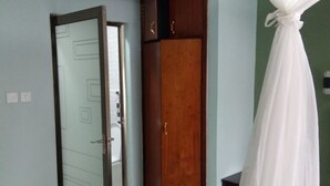 A room with a wardrobe, a bed with a canopy, and a tiled floor. - Jimlizer Hotel (Nairobi)