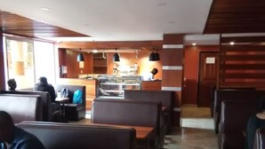 A restaurant with booths and tables, a counter with a display case, and a kitchen area. - Jimlizer Hotel (Nairobi)