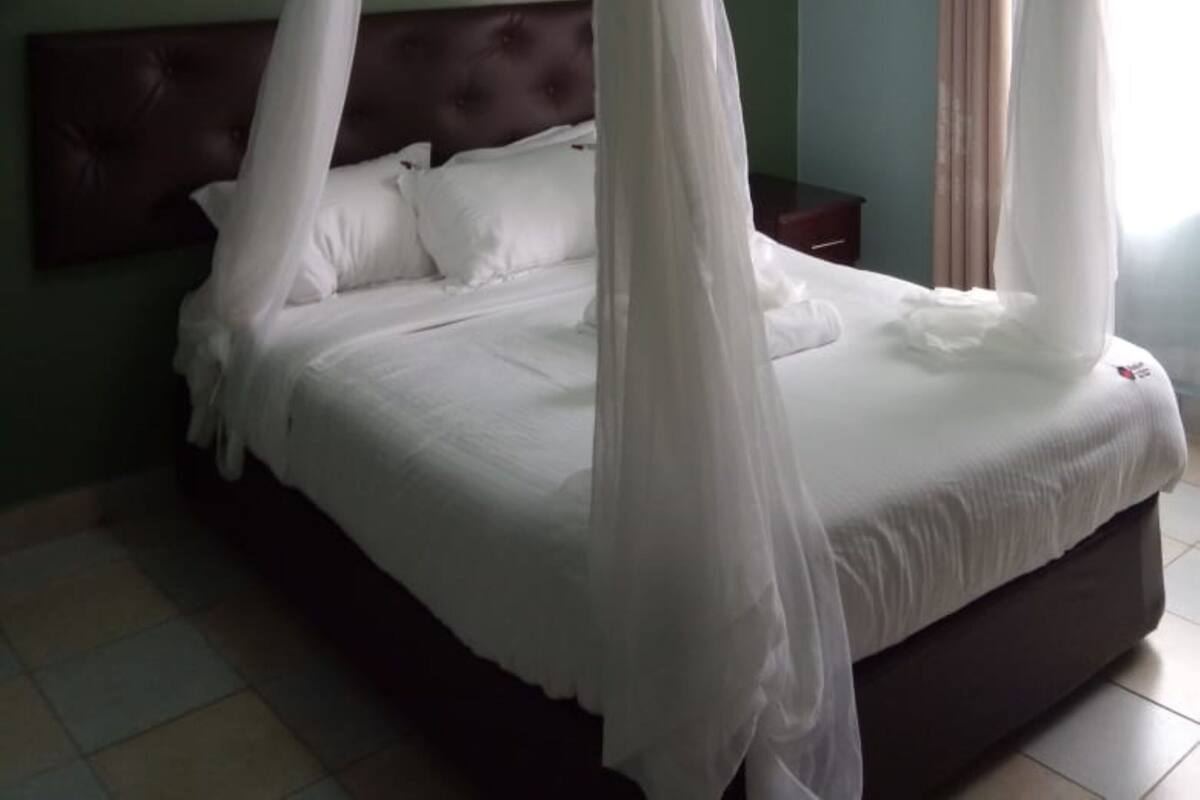 A bedroom with a four-poster canopy bed, a tufted headboard, and a nightstand.