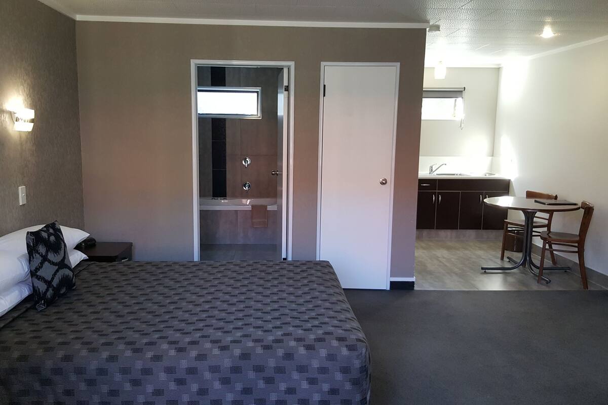 Ein Hotelzimmer mit Bett, Schreibtisch und einem durchgegangenen Tür erkennbaren Badezimmer.