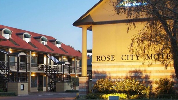 Ein Motel mit rotem Dach und einem Schild, auf dem 'ROSE CITY MOTEL' steht.