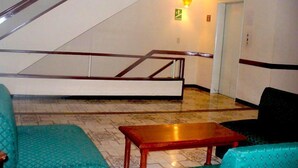 Eine Hotelhalle mit Treppe, einer Rezeption und einer Sitzecke mit stahlblauen Polstersesseln.