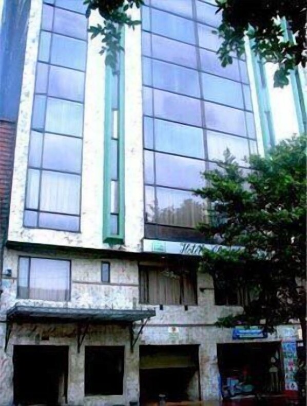 Un edificio de varios pisos con amplios ventanales y un toldo verde.
