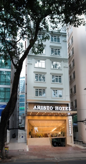 L'ingresso di un hotel con un cartello che riporta 'ARISTO HOTEL' e un servizio di massaggi visibile.