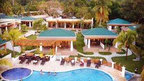 A resort with a large swimming pool, multiple guest rooms, and a mountainous backdrop. - Paraiso Rainforest and Beach Hotel (Omoa)