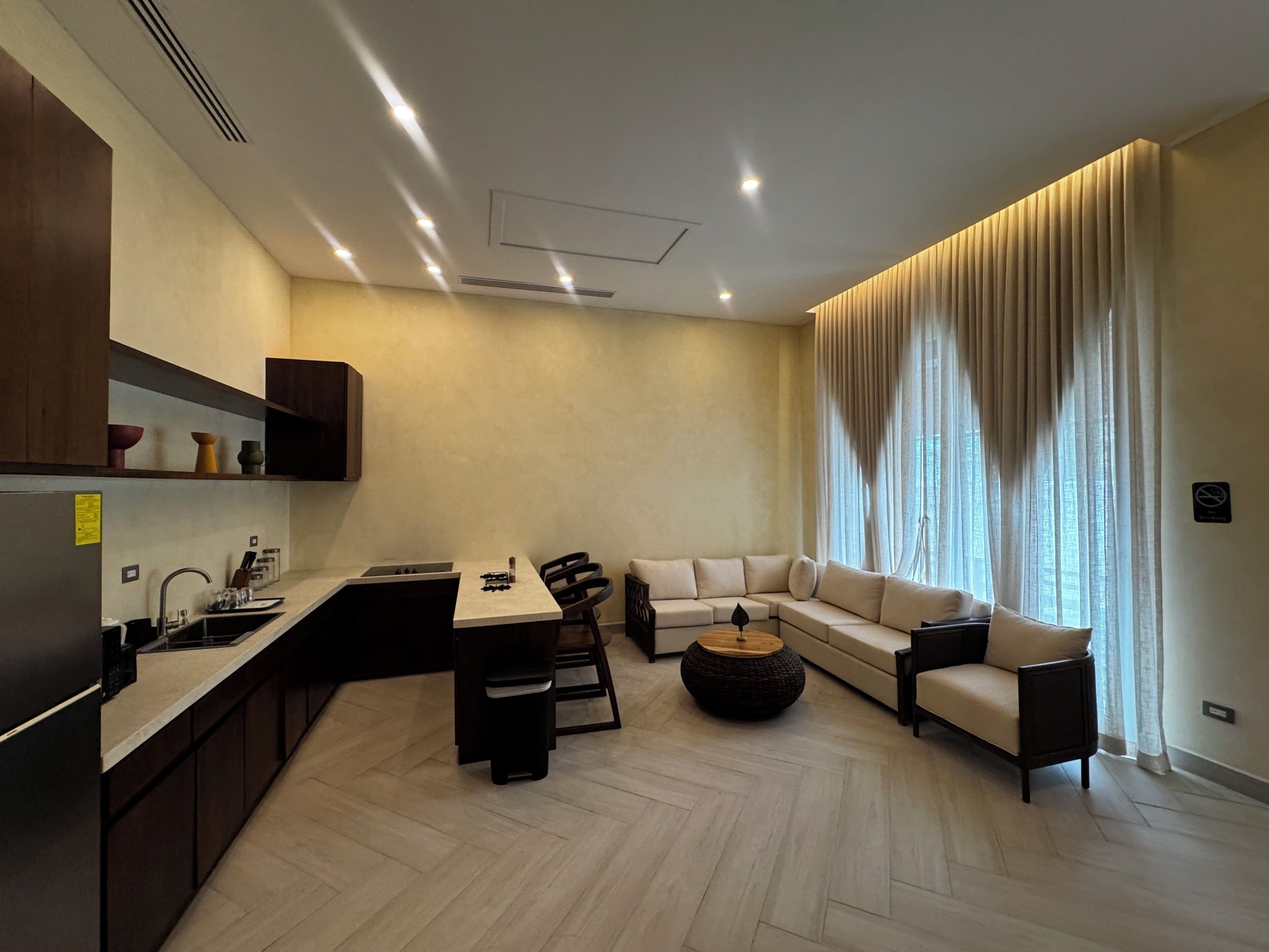 Sala de estar moderna com sofá, mesa de centro e área de cozinha com pia e armários.
