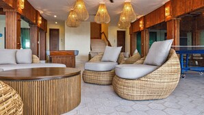 A spacious lobby with wicker furniture, a reception desk, and a ceiling fan. - Paraiso Rainforest and Beach Hotel (Omoa)