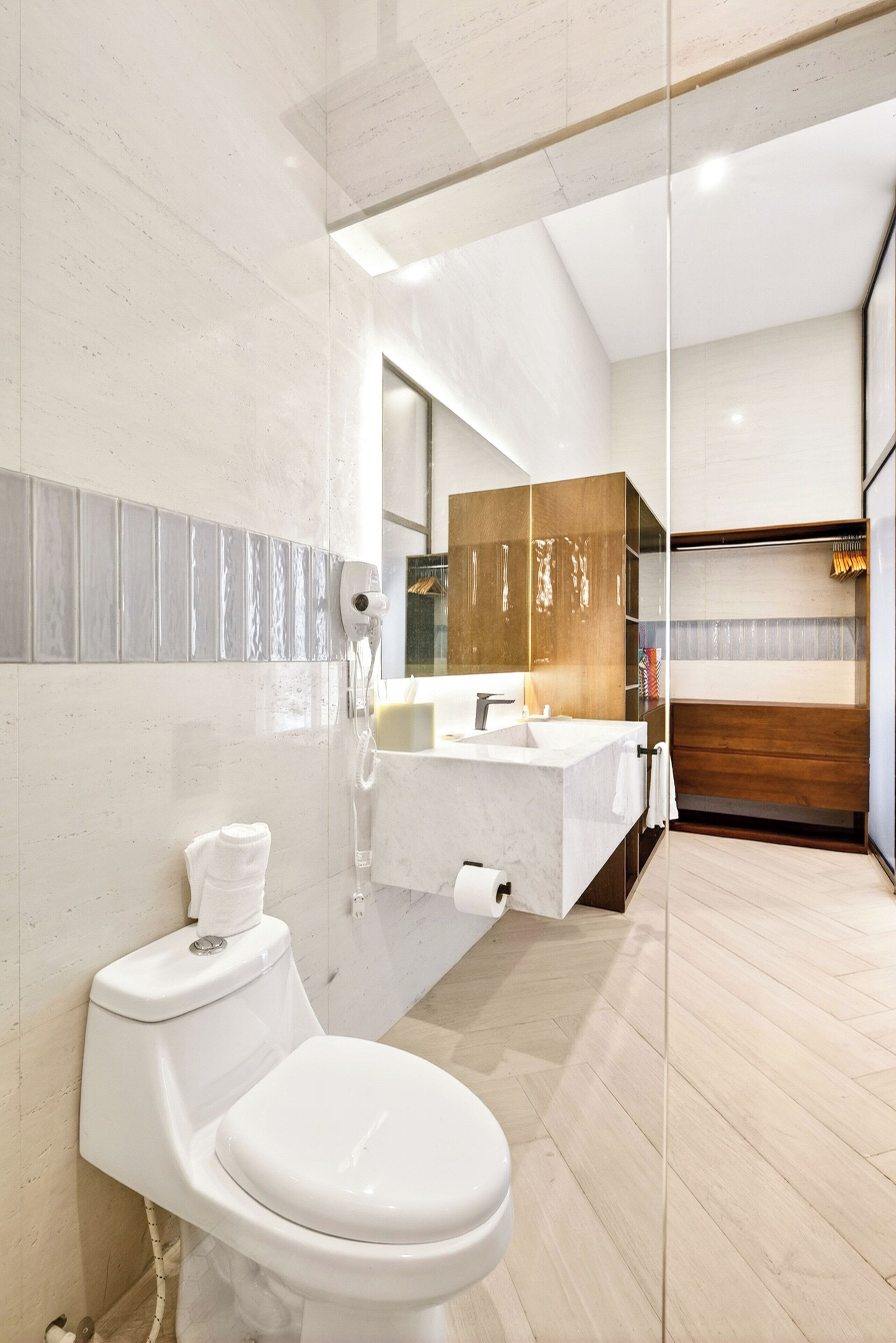 Un baño moderno con inodoro, lavamanos y zona de ducha.