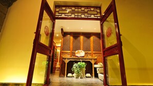 A traditional interior with a wooden reception desk, a large potted plant, and a decorative wall. - Beijing Traditional View Hotel (Beijing)