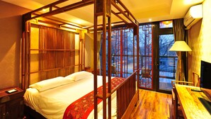 A traditional wooden four-poster bed with a red patterned bed runner, a wooden desk with a chair, and a television. - Beijing Traditional View Hotel (Beijing)